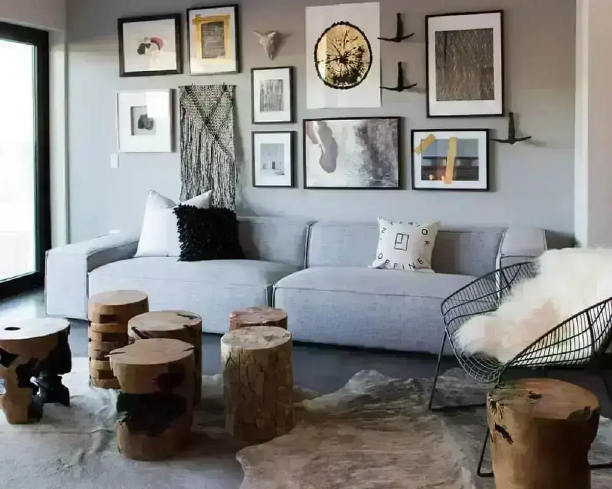 sofá cinza para sala de estar decorada com tapete de couro e troncos de madeira