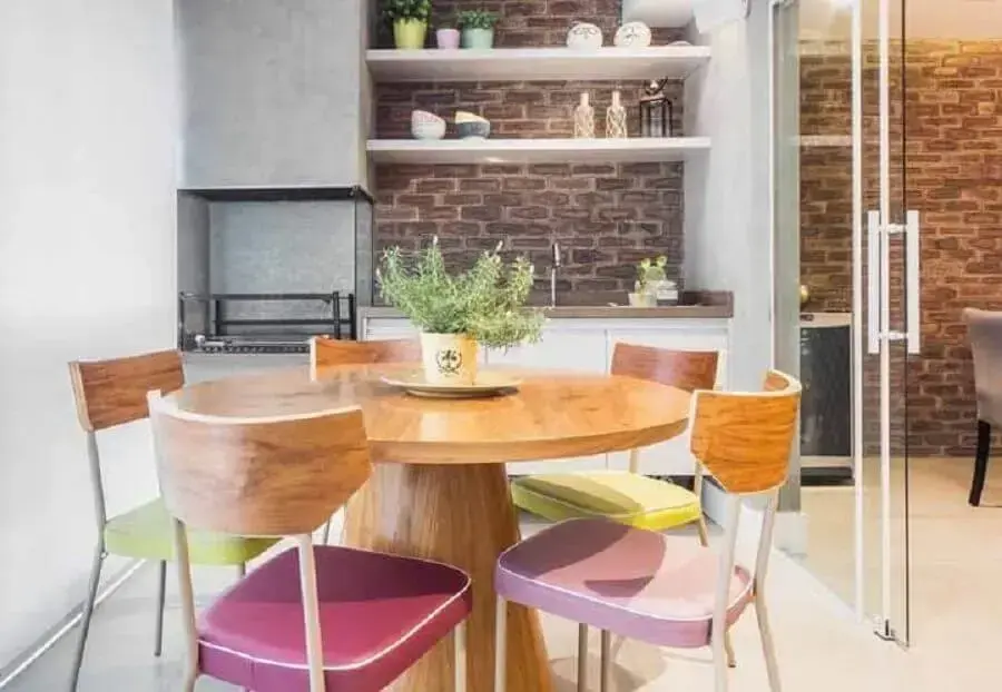 decoração de espaço gourmet pequeno com mesa de madeira redonda e parede de tijolinho Foto Pinterest