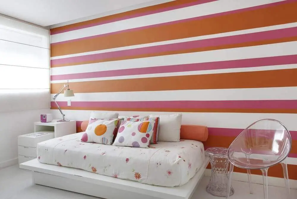 decoração de quarto feminino com papel de parede listrado de rosa laranja e branco