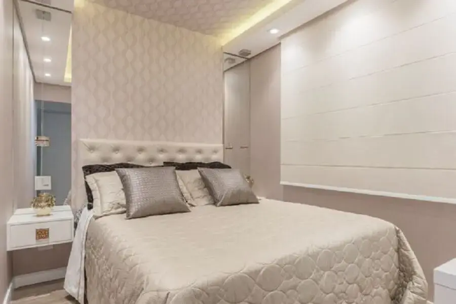 decoração quarto de casal clean com parede revestida de espelho e cabeceira estofada
