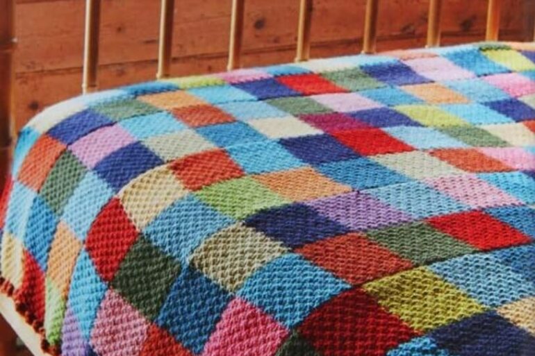 Cama de madeira decorada com colcha de crochê colorida