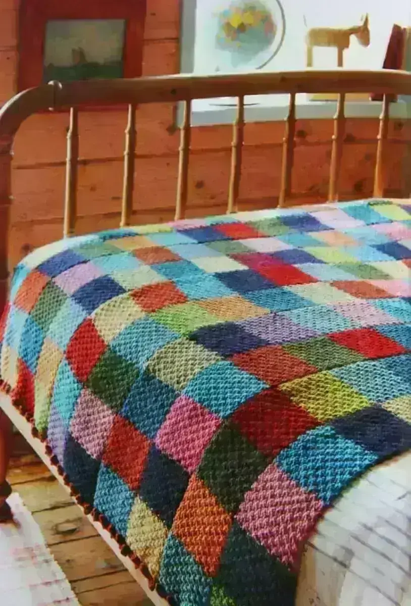 Cama de madeira decorada com colcha de crochê colorida