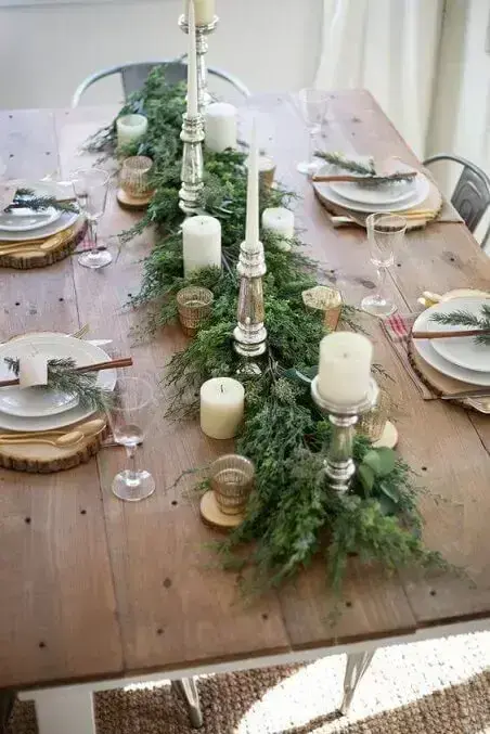 Centro de mesa de jantar rústico com velas e ramos de folhas