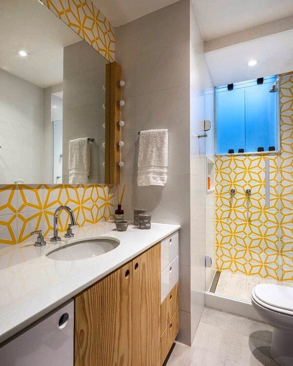 Revestimento de parede em tons de amarelo que iluminam o banheiro. Fonte: PKB Arquitetura