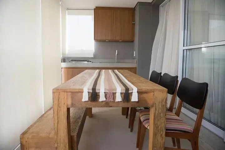 Varanda com mesa e banco de madeira de demolição Projeto de Ronaldo Assim