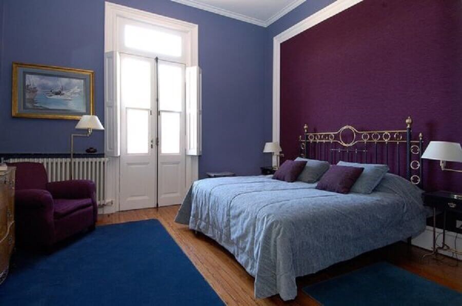 Decoração de quarto de casal com parede roxa e tapete azul