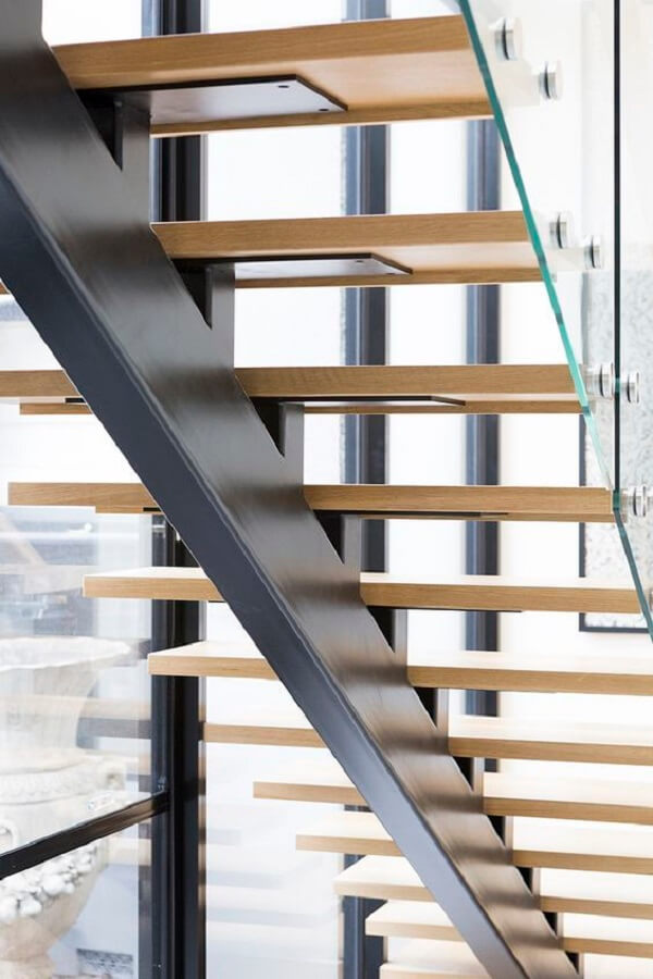 Escada flutuante com degraus de madeira e guarda corpo de vidro. Fonte: Sastairs