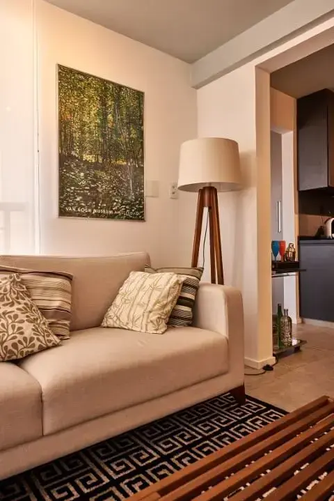 Luminária de madeira tripé ao lado do sofá em sala de estar Projeto de Goup Arquitetura
