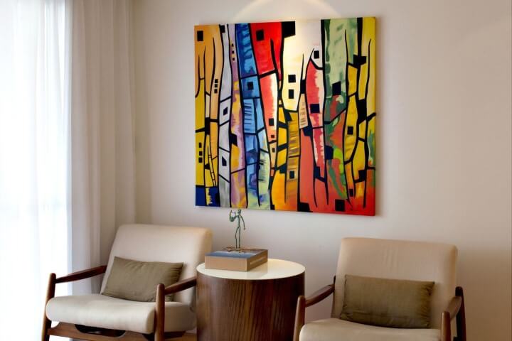 Sala de estar com mesa redonda lateral e quadro colorido Projeto de Rawi Arquitetura