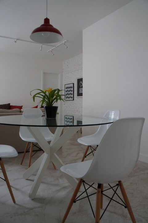 Sala de jantar com mesa redonda de vidro e cadeiras Eames brancas Projeto de P Martino
