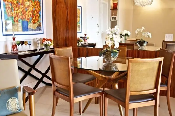 Sala de jantar com mesa redonda de vidro e pés em madeira