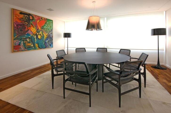 Sala de jantar com mesa redonda e cadeiras pretas Projeto de AMFB Arquitetura