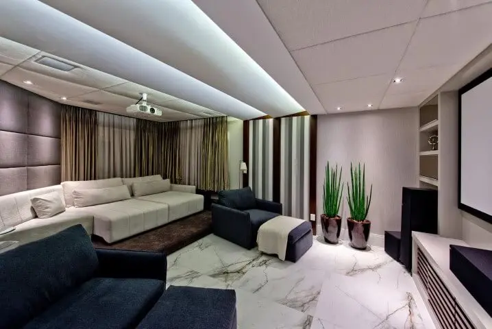 Sala de televisão com sofá retrátil branco e poltronas azuis Projeto de Espaço do Traço