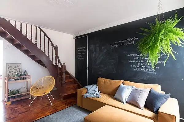 Tinta lousa na parede e escada de madeira que dá acesso aos andares superiores. Fonte: INÁ Arquitetura
