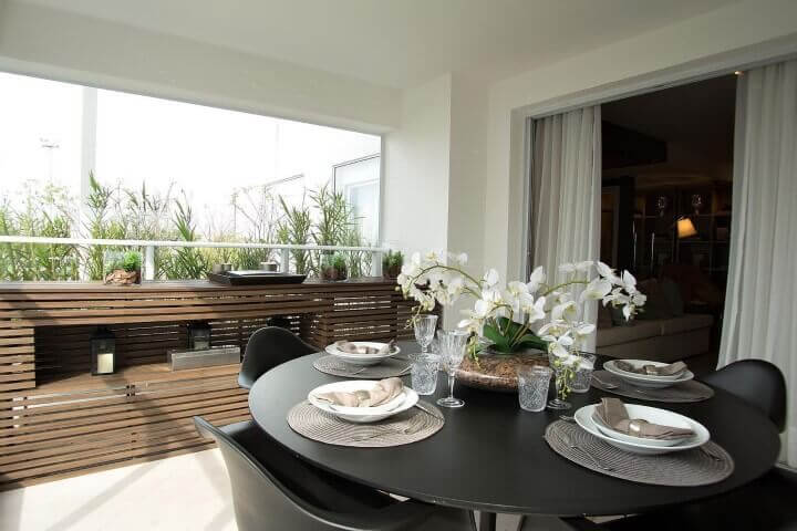 Varanda gourmet com mesa redonda preta e cadeiras da mesma cor Projeto de Carlos Rossi