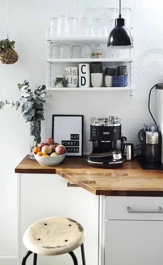 Imagem de um cantinho do café com uma bancada de madeira, duas plantas e utensílios de café