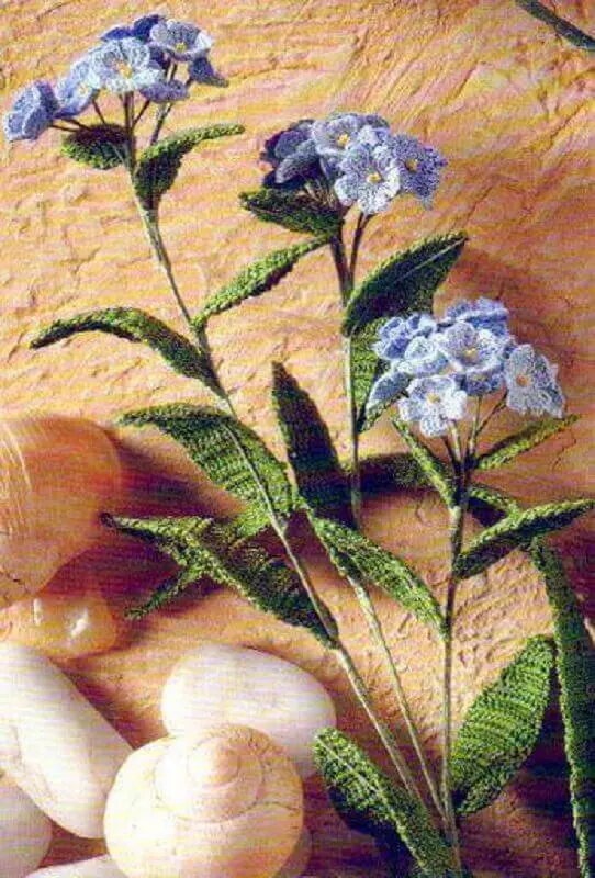 delicado arranjo com flores azuis e folhas em crochê