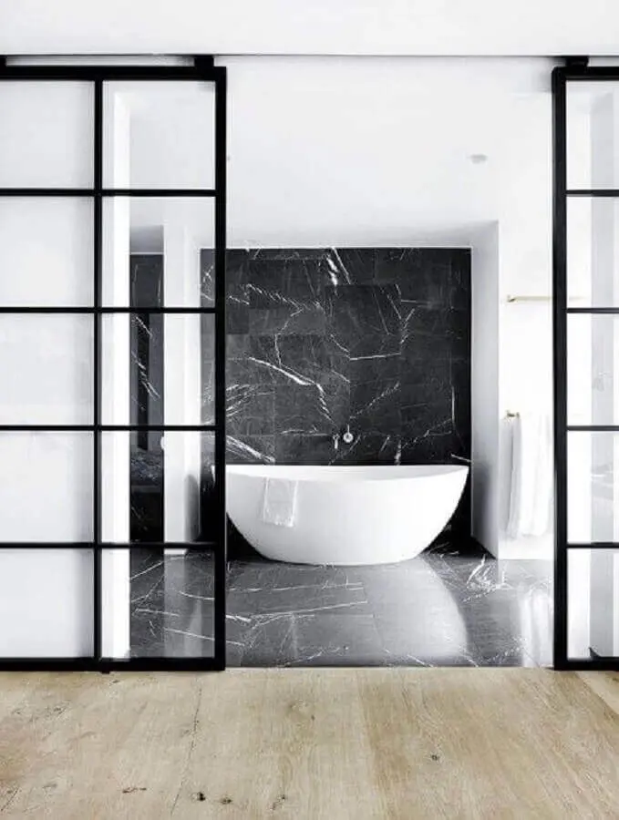 Banheiro decorado moderno com mármore preto e banheira branca - Foto space cph