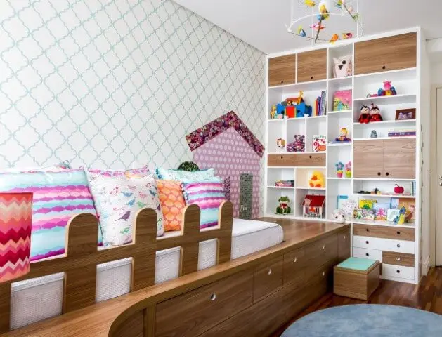 Quarto de bebê menina com almofadas coloridas e estante com nichos Projeto de Anna Maria Parisi