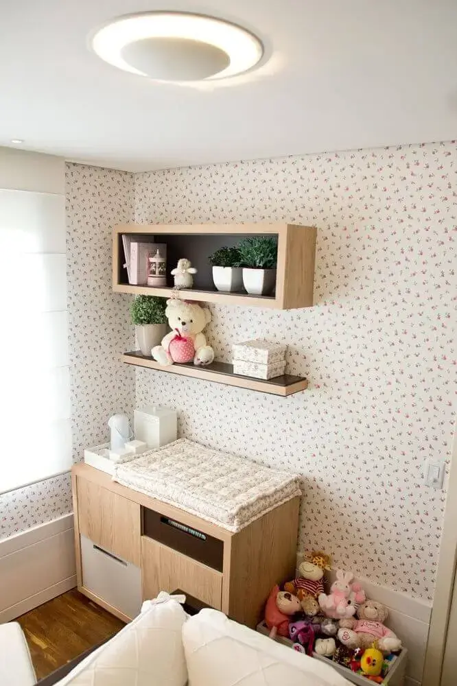 decoração com papel de parede florido e nichos para quarto de bebê de madeira