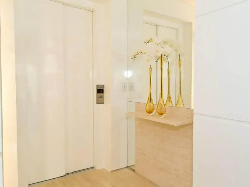clean para hall de entrada de apartamento com parede espelhada e vasos de flores