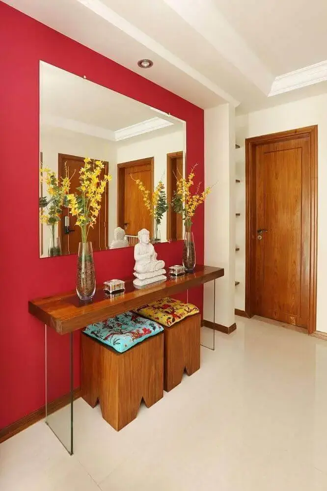 hall de entrada com parede vermelha espelho e aparador com base de vidro
