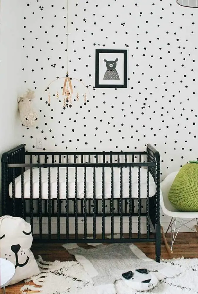 quarto de bebê pequeno decorado com berço preto e papel de parede de bolinha