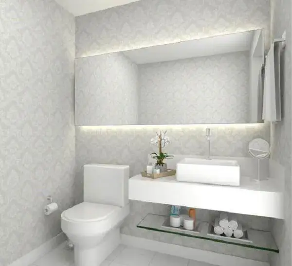 Banheiro com decoração clean conta com prateleira de vidro
