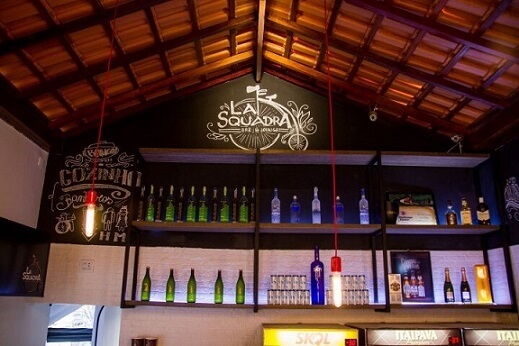 Bar de parede com prateleiras altas com bebidas Projeto de Bianchi Lima