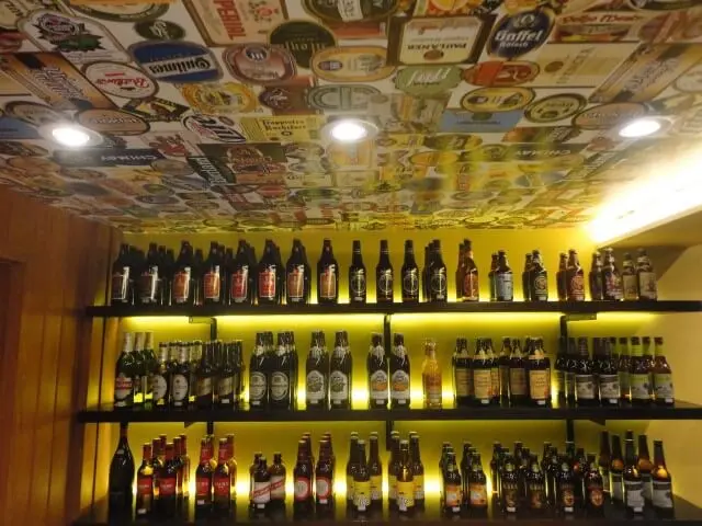Bar de parede com rótulos de cervejas no teto Projeto de Maria Helena Torres