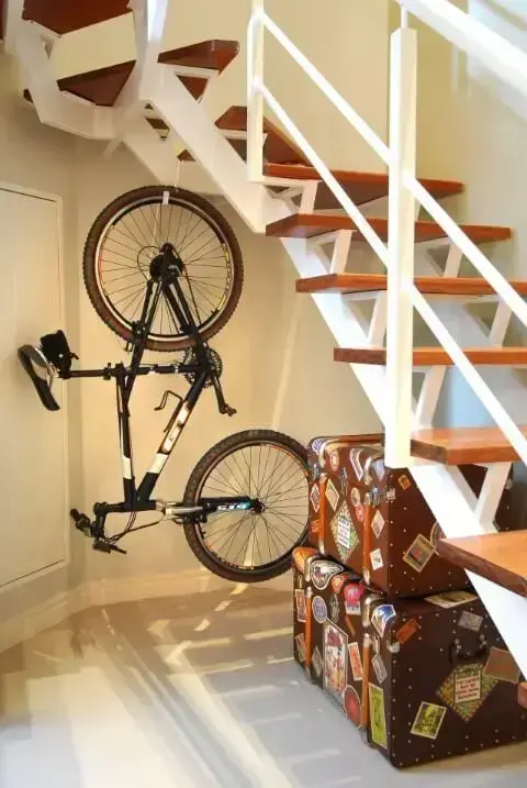 Loft com bicicleta e malas embaixo da escada Projeto de Flávia Portela