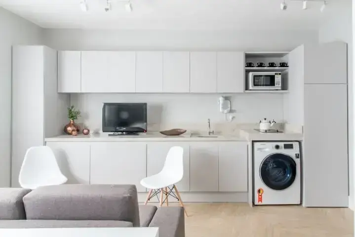 Loft com cozinha planejada com lavanderia ligada à sala Projeto de Renata Romeiro