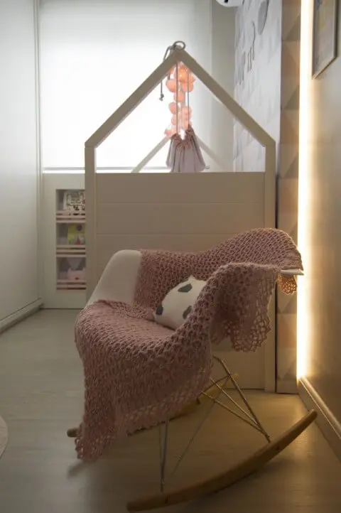 Quarto de bebê com manta em tons de rosa em cadeira de balanço Projeto de Debora Marquardt