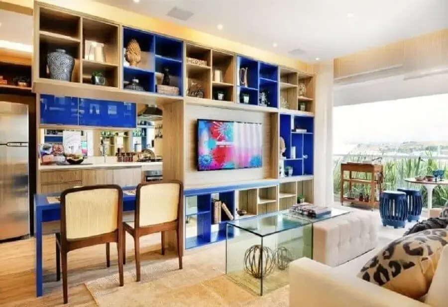 Sala de estar com estante de madeira com módulos azul royal Foto Quitete Faria