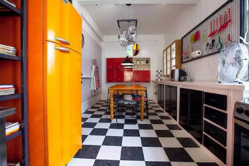 decoração para cozinha retrô com piso xadrez preto e branco e geladeira laranja
