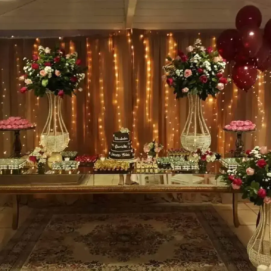 decoração sofisticada para festa de 15 anos com pisca pisca mesa espelhada e grande arranjo de flores 