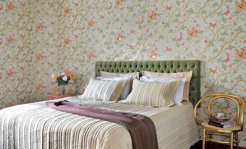 quarto decorado com cabeceira capitonê verde e papel de parede floral