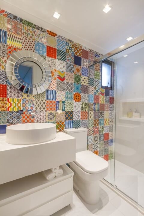 Banheiro com ladrilhos coloridos na parede e bacia com caixa acoplada branca Foto de Bordin Soares