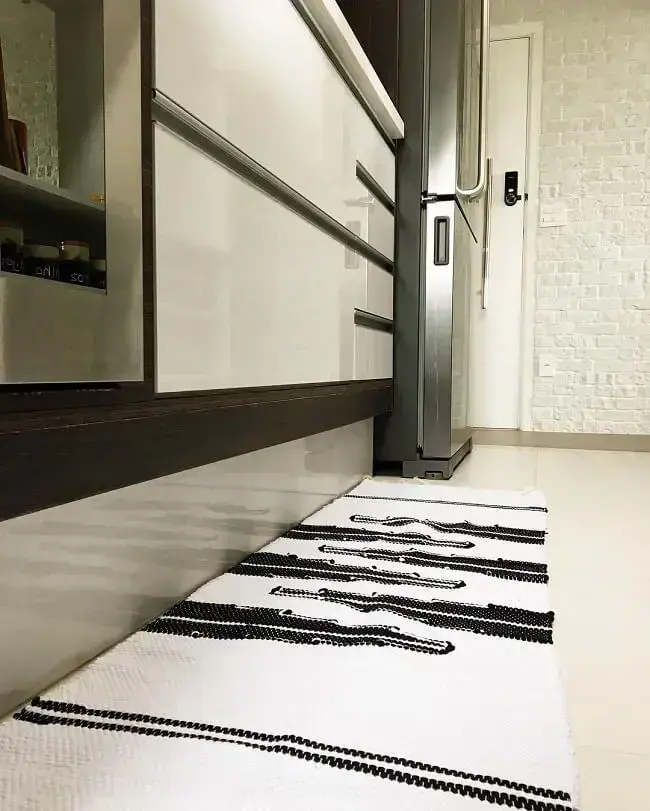 Os nuances em preto e branco do tapete para cozinha se conectam com a decoração do espaço. Fonte: Apartamento 155