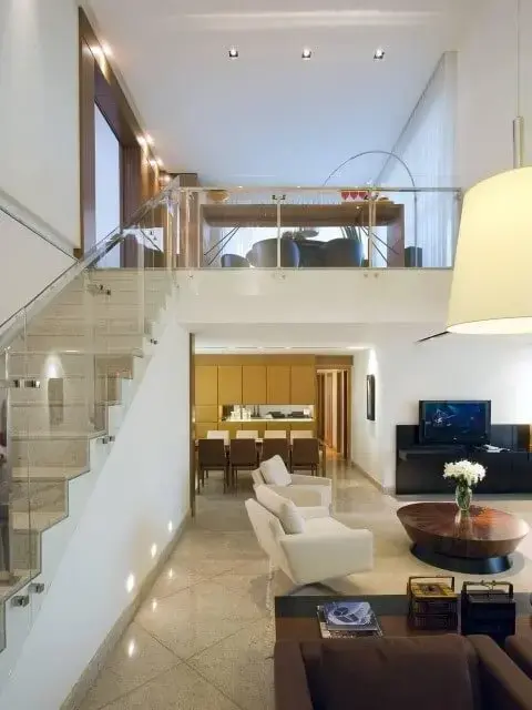 Sala de estar com pé direito alto e escada de granito Projeto de Renata Basques