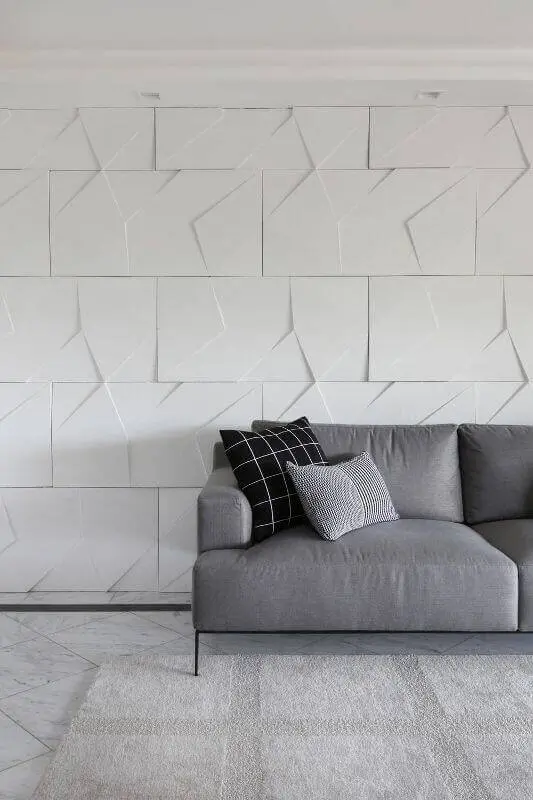 Sala moderna com parede com gesso 3D atrás do sofá cinza Projeto de Bianchi Lima