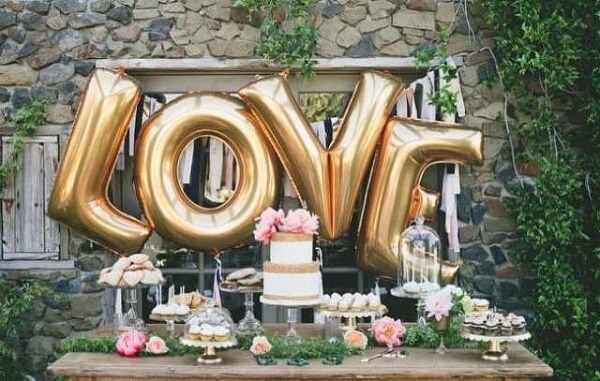 Balões metálicos na mesa do bolo transforma a decoração de noivado