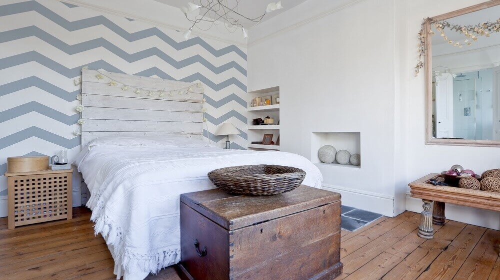 criado mudo de madeira para quarto de casal com papel de parede azul e branco e cabeceira de madeira Foto dobrzemieszkaj