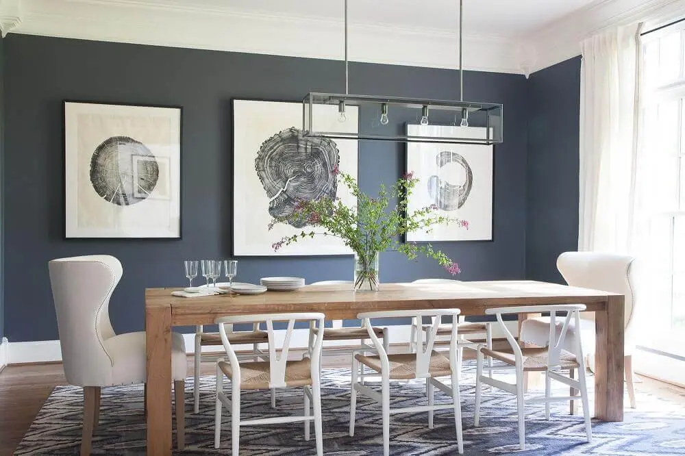 decoração com modelos diferentes de cadeiras para sala de jantar modernas com quadros na parede e mesa de madeira Foto Lonny
