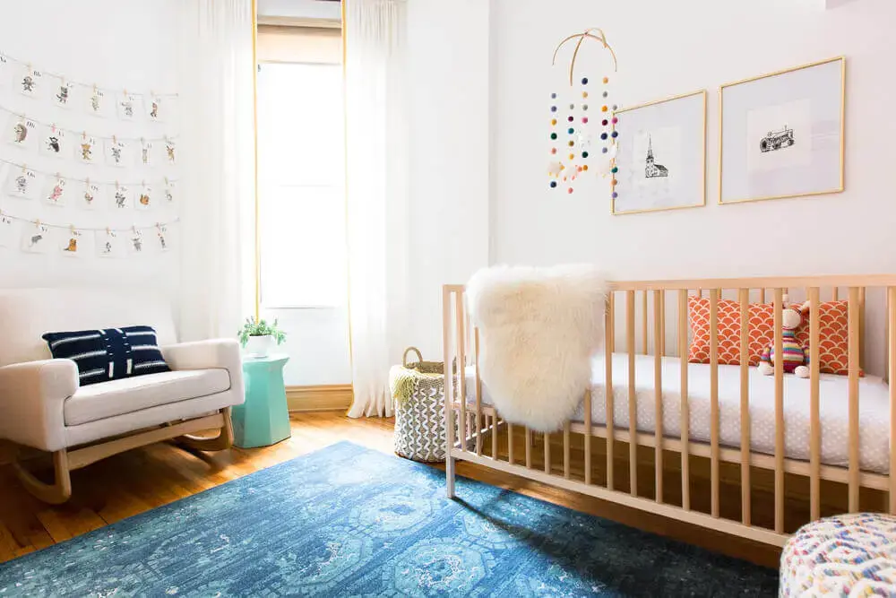 modelo confortável de cadeira de amamentação moderna para quarto de bebê com tapete azul Foto Rehabitat Interiors