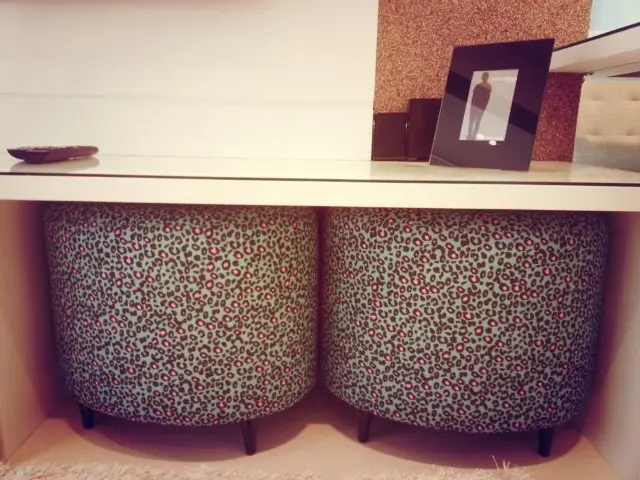 Decoração de sala com puffs de oncinha encaixados sob mesa Projeto de Condecorar
