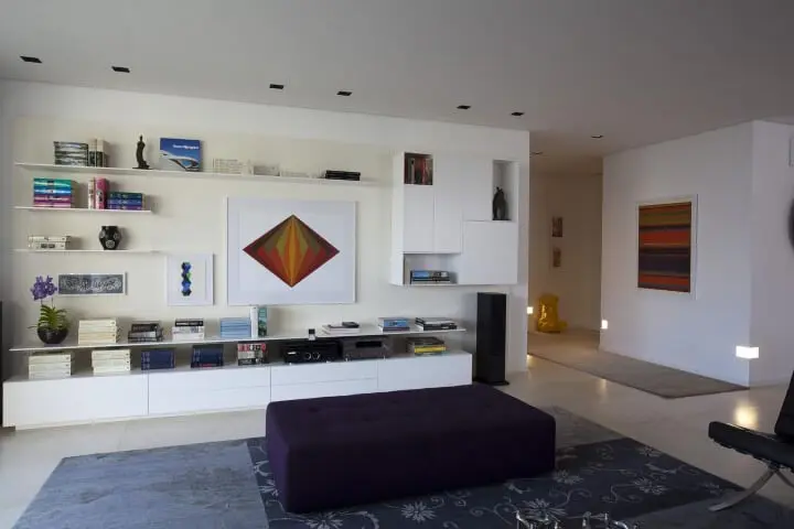 Decoração de sala de estar com várias pradeleitas e nichos com livros e objetos decorativos Projeto de AMC Arquitetura