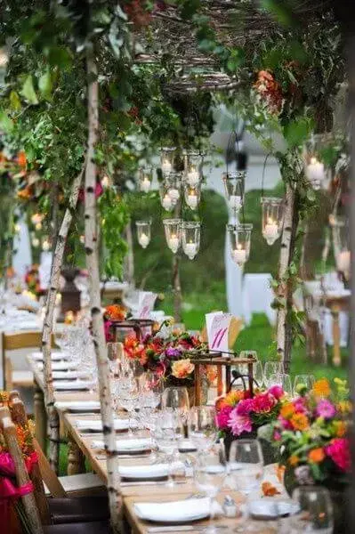 Festa externa com tema jardim encantado e mesas longas com decorações de flores e folhas Foto de Pinterest