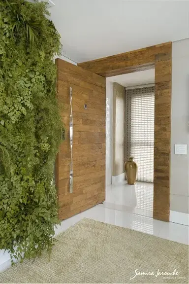 Hall com porta de madeira de demolição e parede de jardim vertical Projeto de Samira Jarouche