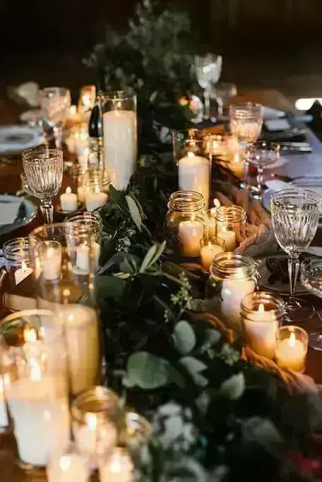 Mesa de ceia de natal com várias velas e ramos de árvores Foto de 100 Layer Cake